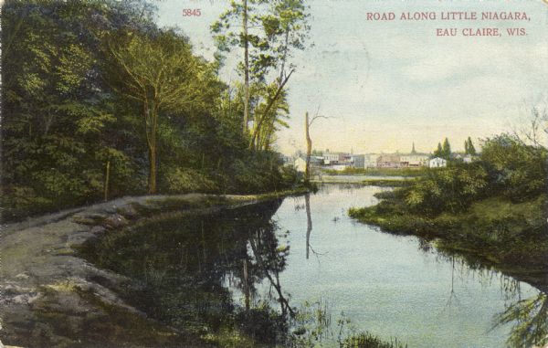 Colored photographic postcard view of an unpaved road along the Little Niagara River. Eau Claire buildings are in the distance. Caption reads: "Road Along Little Niagara, Eau Claire, Wis."