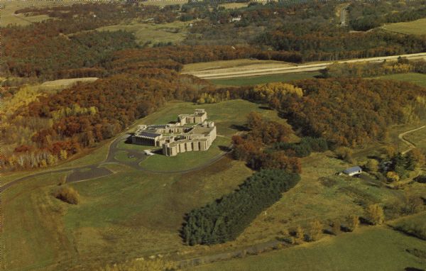 Aerial view of St. Bede's Priory and High School, including the surrounding country landscape. There is a highway behind the buildings. The Priory is the Motherhouse for Sisters of St. Benedict, who conduct the girls' boarding and day school.