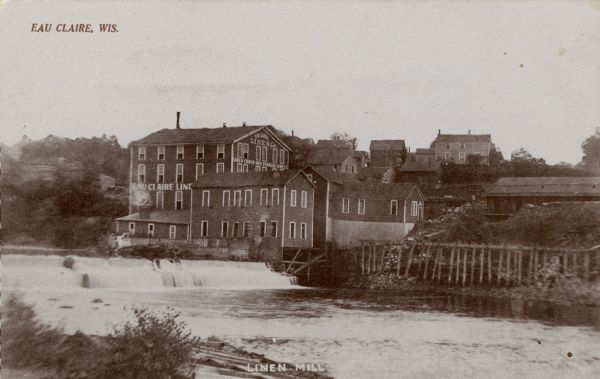View across water towards the Linen Mill along the banks of the Eau Claire River. Caption reads: "Eau Claire, Wis." and "Linen Mill."