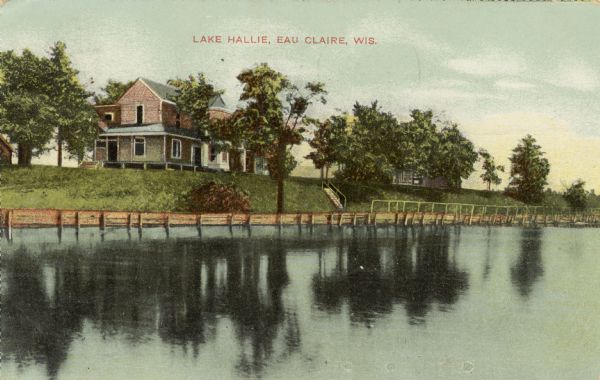 A color enhanced photographic postcard view of Lake Hallie, with a large frame house along the opposite shoreline. Caption reads: "Lake Hallie, Eau Claire, Wis."
