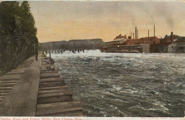 Colorized photograph of the dells, the dam and the paper mills on the Eau Claire River. A man is standing on a wooden pier along the shoreline on the left.