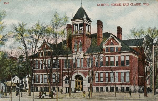 Colorized postcard of a red brick elementary school with a few students gathered in front. A bell tower is above the arched entrance. Caption reads: "School House, Eau Claire, Wis."