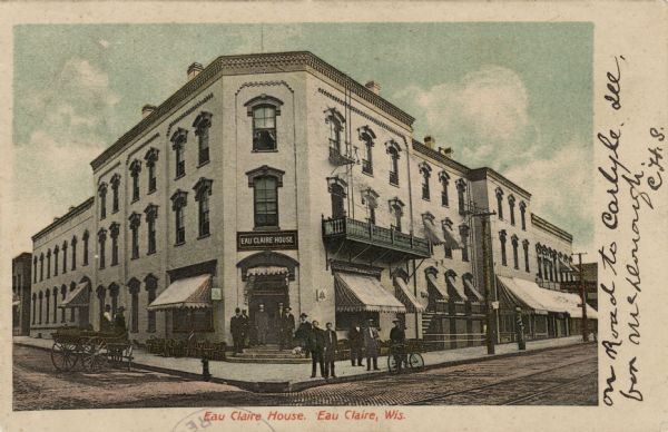 Colorized photographic postcard from street towards the Eau Claire House on a street corner. There is a group of men standing in front. A buggy is along the curb on the left, and a man is standing in the street with a bicycle on the right. Caption reads: "Eau Claire House, Eau Claire, Wis."