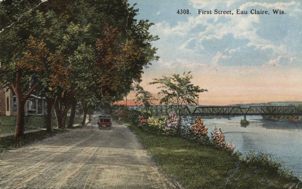 Colorized view of First Street along the Chippewa River. Homes are on the left along the tree-lined street. A bridge is crossing the river in the distance on the right. Caption reads: "First Street, Eau Claire, Wis."