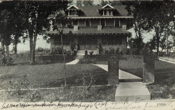 Black and white photographic postcard of a two-story brick house with a large front yard. Caption reads: "One of Edgerton's Fine Residences, Edgerton, Wis."