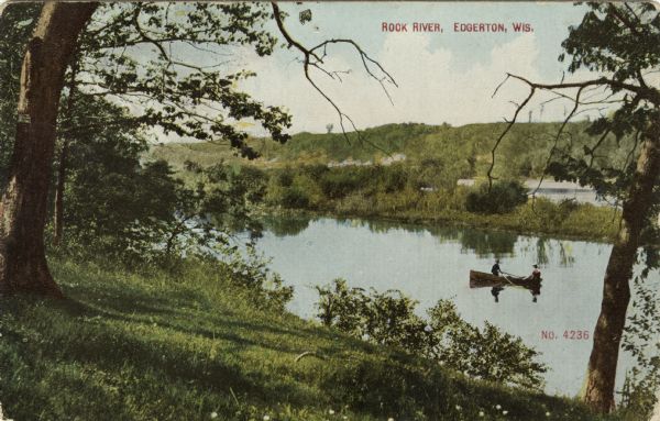 Colorized view from grassy shoreline of the Rock River, with a couple in a rowboat. Trees are reflected in the calm water. Caption reads: "Rock River, Edgerton, Wis."