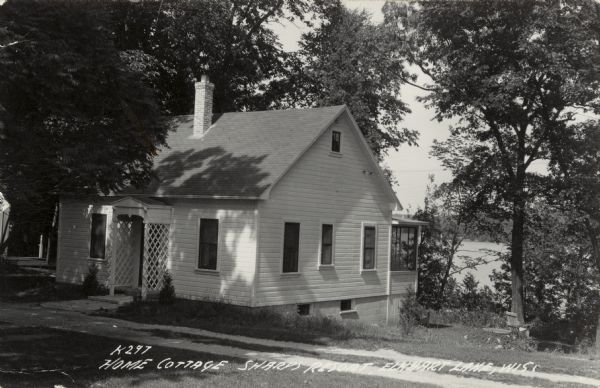 A small white cottage with a trellised entrance on the shore of Elkhart Lake. Caption reads: "Home Cottage, Sharp's Resort, Elkhart Lake, Wis."