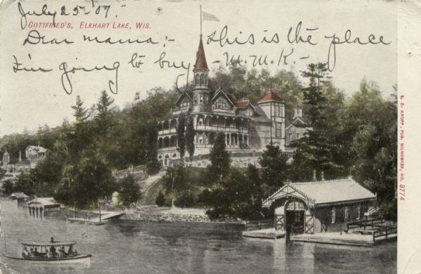 Colorized elevated view of a large lakeside hotel inspired by castles on the Rhine. A small excursion boat is passing the dock and boathouse. Caption reads: "Gottfried's, Elkhart Lake, Wis."
