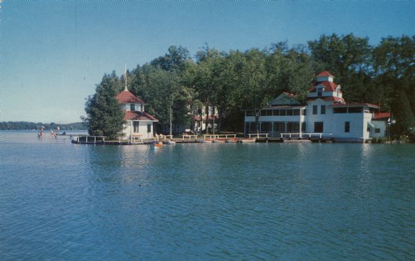 Kodachrome print of a lakeside hotel. Text on reverse reads: "Hotel Camp Brosius on beautiful Elkhart Lake. Dining room, lounge, boat area, and round house. Complete hotel and recreational facilities."