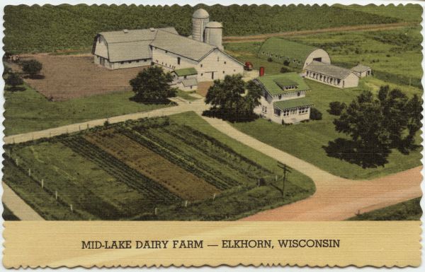 Aerial view of a dairy farm with white barns and a white house. Caption reads: "Mid-Lake Dairy Farm — Elkhorn, Wisconsin."