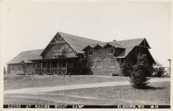View towards a two-story log lodge. Caption reads: "Lodge at Racine Scout Camp, Elkhorn, Wis."