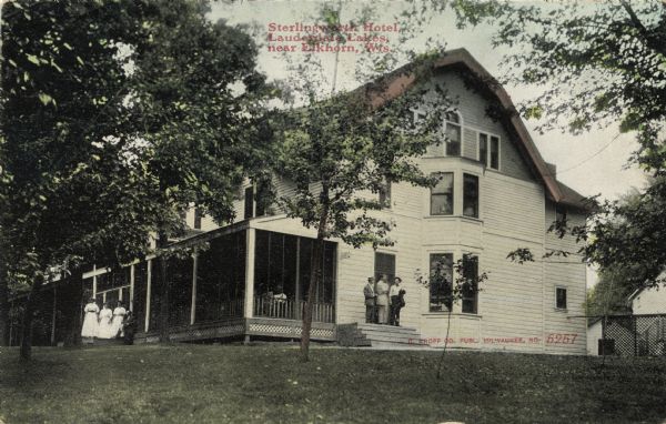 Colored view across lawn towards a hotel with a screened-in porch. Three women are standing at the entrance on the left. In the center are three men standing at a side door. Caption reads: "Sterlingworth Hotel, Lauderdale Lakes, near Elkhorn, Wis."
