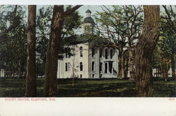 Colorized view through trees toward the Court House, with columns at the entrance, arched windows and a bell tower. Caption reads: "Court House, Elkhorn, Wis."