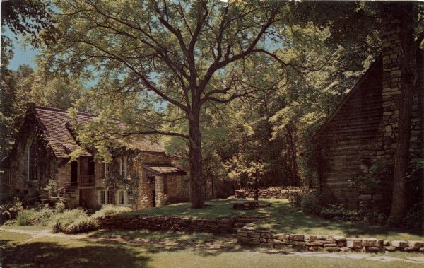 Color view of The Clearing, a folk art school in Ellison Bay. A stone building and a log building are under a grove of trees.