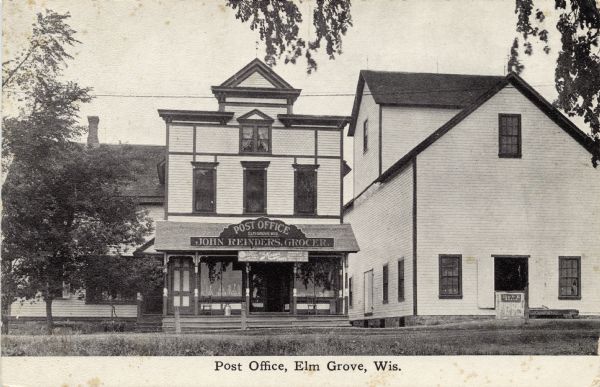 View across street towards the Elm Grove Post Office and John Reinders Grocery Store. Caption reads: "Post Office, Elm Grove, Wis."