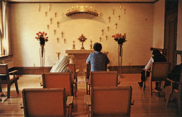 Interior view from the rear of the Chapel of Perpetual Adoration, part of the Visitation Convent. Four people are sitting or kneeling.