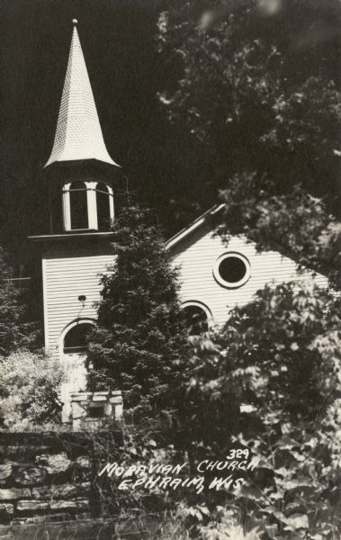 The Moravian Church partially obscured by trees. Caption reads: "Moravian Church, Ephraim, Wis."