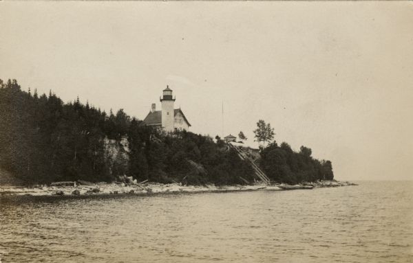 View across water towards the steep shoreline and lighthouse at Eagle Harbor.