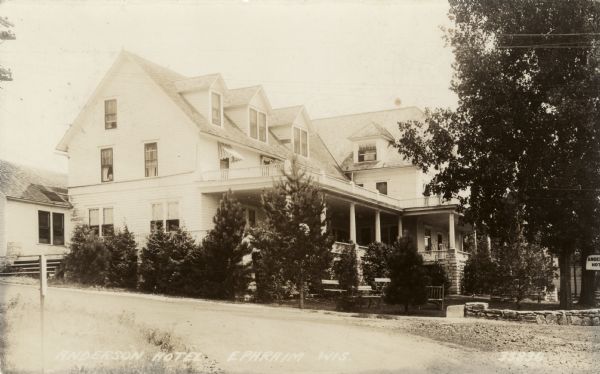 Exterior view of the Anderson Hotel. The building is a two-story wooden structure with a gabled roof, balcony and porch. Caption reads: "Anderson Hotel, Ephraim, Wis."