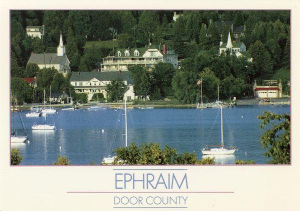 View of Ephraim from Eagle Bay. Caption reads: "Ephraim, Door County." Text on reverse reads: "Ephraim is a charming town on Door County's western shoreline. In this picture, the steeples of the Lutheran and Moravian churches rise above the scenic harbor."