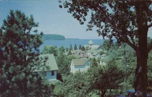 Kodachrome reproduction of the view over the rooftops of Ephraim towards Eagle Bay.

Text on reverse reads: "Portraying the beauty and charm of picturesque Ephraim, Wisconsin, the Resort Center of Door County. Ephraim, meaning 'The Very Fruitful' was settled by the Moravians in 1853."