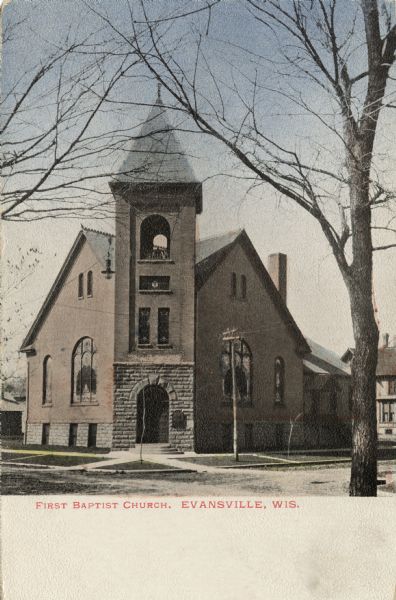 Hand-colored view from intersection towards the First Baptist Church, with a bell-tower above the corner entrance. Caption reads: "First Baptist Church, Evansville, Wis."