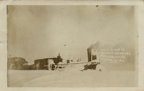 Sepia-toned view of a snow-bound train. Caption reads: "Snow Blockade between Fennimore and Lancaster Winter of 1910."