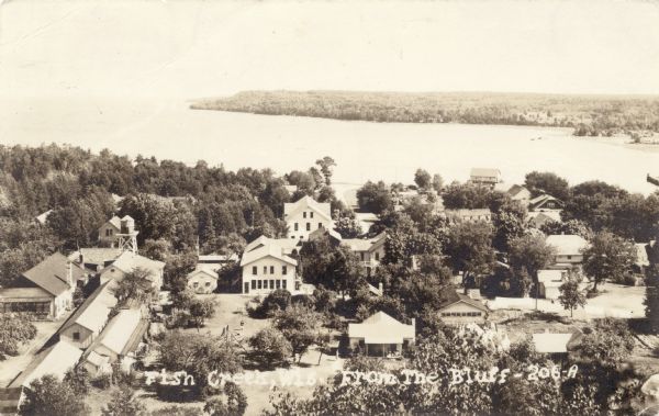 Elevated view of Fish Creek and Green Bay. Dwellings are in the foreground. The Peninsula State Park is across the bay. Caption reads: "Fish Creek, Wis. From the Bluff".