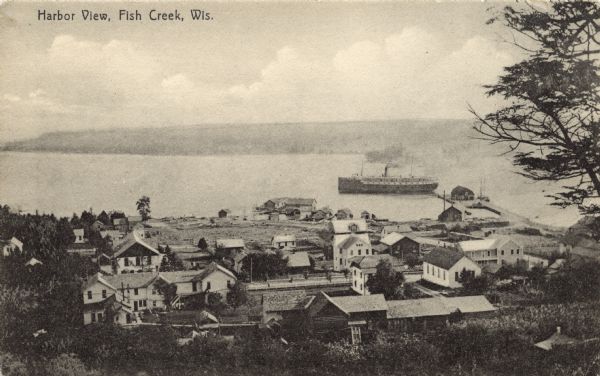 Elevated view from hill of Fish Creek and its harbor. A steamer is near the dock. The Peninsula State Park is across the bay. Caption reads: "Harbor View, Fish Creek, Wis."