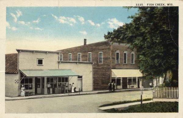 Street scene with a group of people gathered in front of a store with a public telephone. Caption reads: "Fish Creek, Wis."