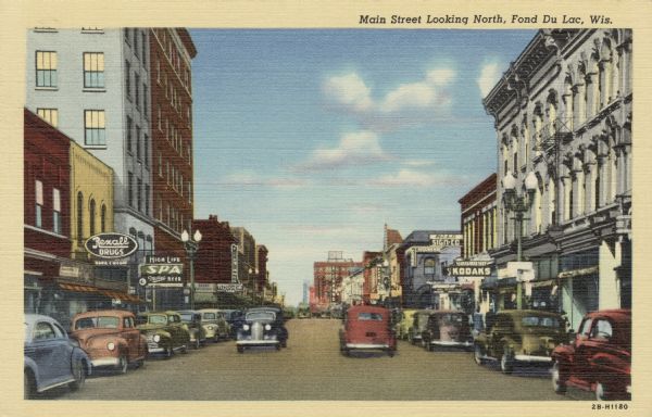 View of Main Street with automobiles in the street and parked along the curbs. Caption reads: "Main Street Looking North, Fond du Lac, Wis."