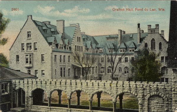 Elevated view of Grafton Hall. In the foreground is a stone arch covered walkway between two buildings, and a courtyard. Caption reads: "Grafton Hall, Fond du Lac, Wis."