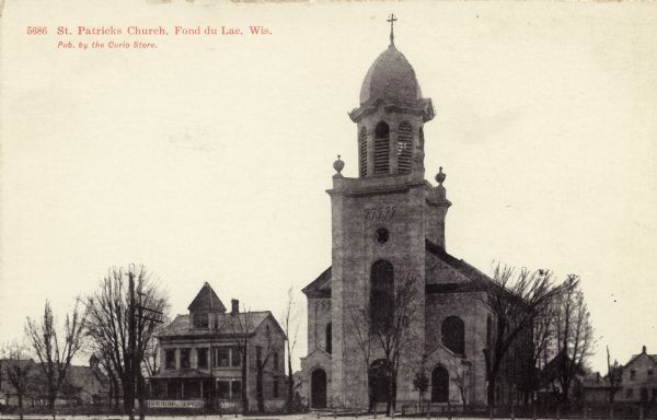 Black and white view of the exterior of St. Patrick's church and the parsonage next door. Caption reads: "St. Patrick's Church, Fond du Lac, Wis."