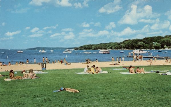 Color postcard of a bathing beach on Lake Geneva. Text on reverse reads: "Fontana lies at the west end of Geneva Lake with an excellent beach. Large spacious lawn and sandy beach for the sun bather."