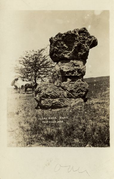 View of Lone Rock. Two people are sitting in a horse-drawn buggy near a tree in the background on the left. Caption reads: "'Lone Rock' Near Footville, Wis."