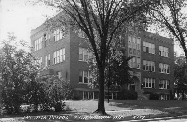 Black and white view from street towards the three-story brick high school. Caption reads: "Sr. High School, Ft. Atkinson, Wis."