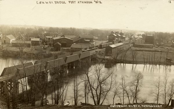 Elevated view of the railroad bridge over the Rock River at Ft. Atkinson. Wilcox Lumber is on the opposite shoreline. Caption reads: "C. & N.W. Railway Bridge, Fort Atkinson, Wis."