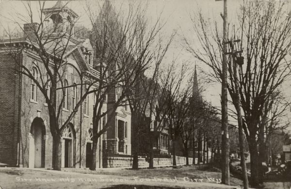 View of the City Hall and high school on a tree-lined street. Caption reads: "City Hall and High School, Fountain City, Wis."