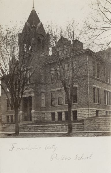 Exterior view of the public school — a two-story brick building with a bell tower.