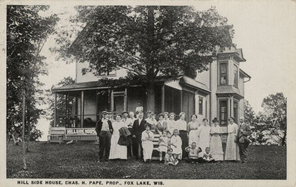 View of "Hillside House" with a group of men, women and children gathered on the lawn under a tree. Caption reads: "Hill Side House, Chas. W. Pape Prop., Fox Lake, Wis."