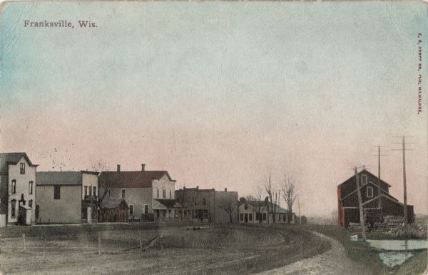 Hand-colored scene of central Franksville. View down road towards dwellings and businesses. Caption reads: "Franksville, Wis."