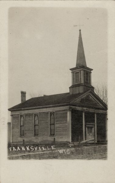 A wooden church with stained glass windows and a steeple. Caption reads: "Franksville, Wis." Note on reverse reads: "Burned Jan 10, 1919."