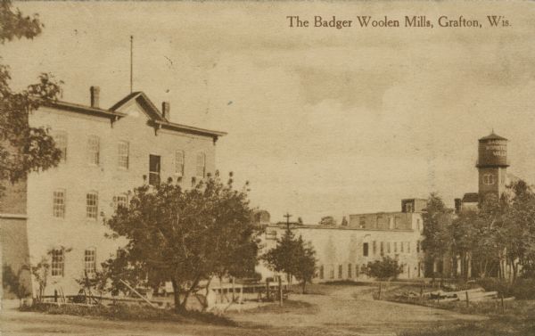 View toward the mills with a water tower on the right. Caption reads: "The Badger Woolen Mills, Grafton, Wis."