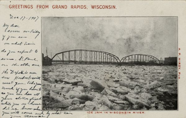 View of an ice jam near a Grand Rapids bridge in the Wisconsin River. Caption at top reads: "Greetings from Grand Rapids, Wis." Caption at bottom reads: "Ice Jam in Wisconsin River."