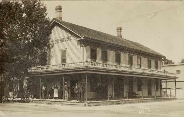 View from street of the Junction House hotel. There is a group of men on the porch. Caption reads: "Genoa Junction, Wisc."