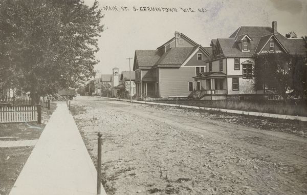 View down a street lined with houses and a church. Caption reads: "Main Street, S. Germantown, Wis."