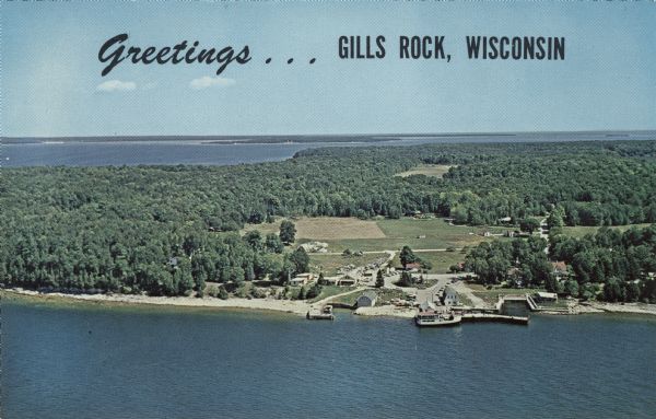A color aerial view of Gills Rock from Green Bay. Washington Island and Lake Michigan are along the horizon. An excursion boat is docked at the landing. Caption reads: "Greetings . . . Gills Rock, Wisconsin."