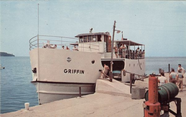 Color postcard of a Washington Island ferry docked at Gills Rock, with an automobile in the hold and tourists on board.