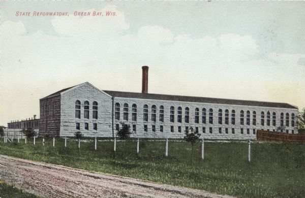 View across road towards the gray stone reformatory. Caption reads: "State Reformatory, Green Bay, Wis."