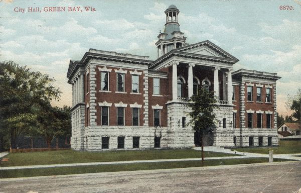 View from street towards the old city hall. The building is of brick and stone, with columns above the arched entrance. Caption reads: "City Hall, Green Bay, Wis."